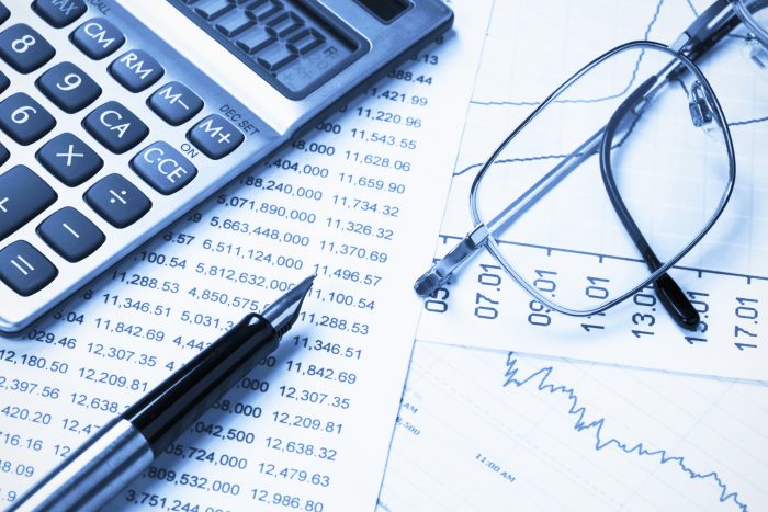 calculatrice, stylo et lunettes sur fiches de budgets