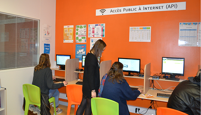 Jeunes filles aux cheveux longs aidant des personnes dans leurs démarches sur Internet dans la Maison France Services de la Bretagne romantique